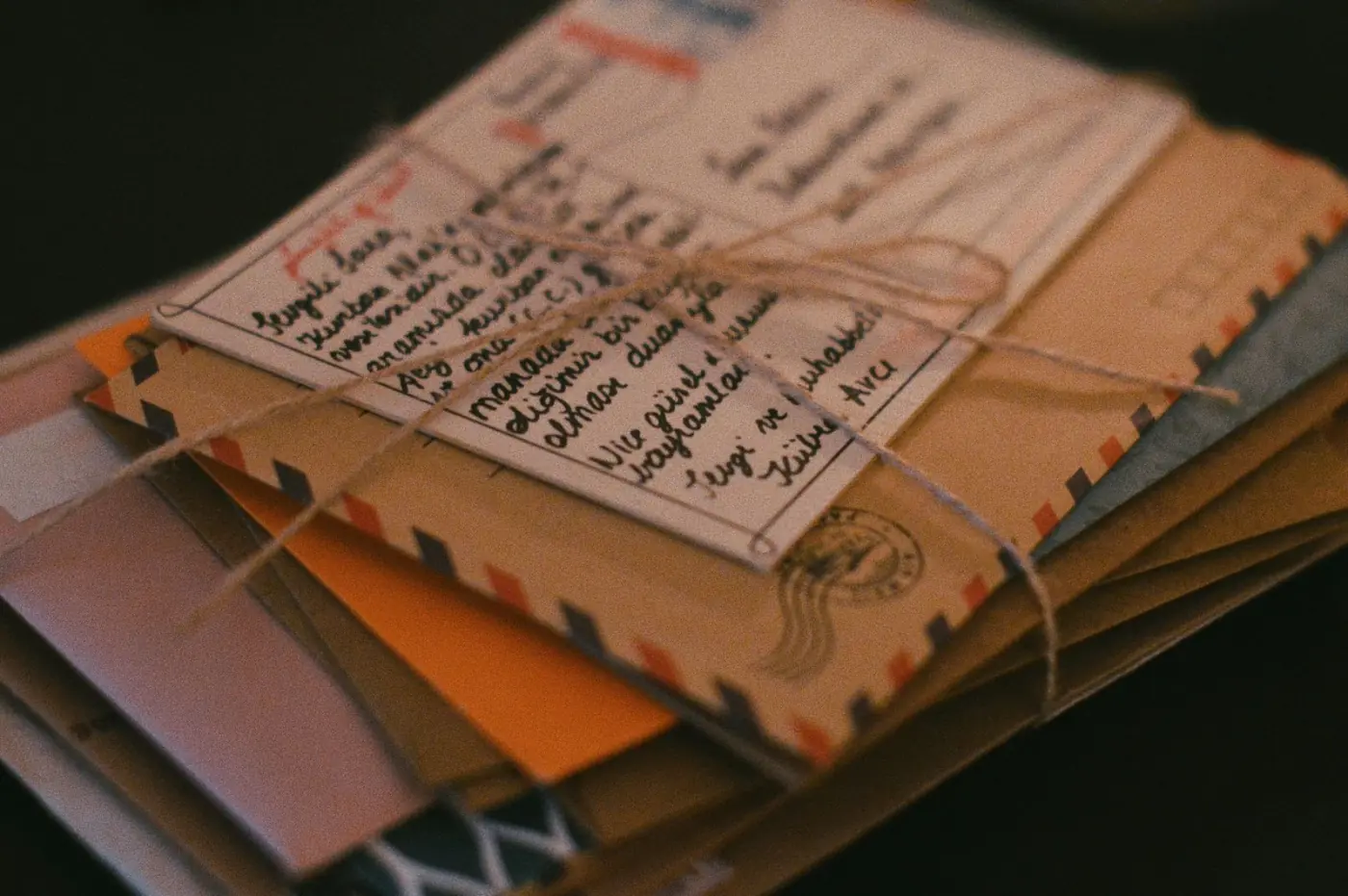 A bundle of old letters tied with twine on a dark surface