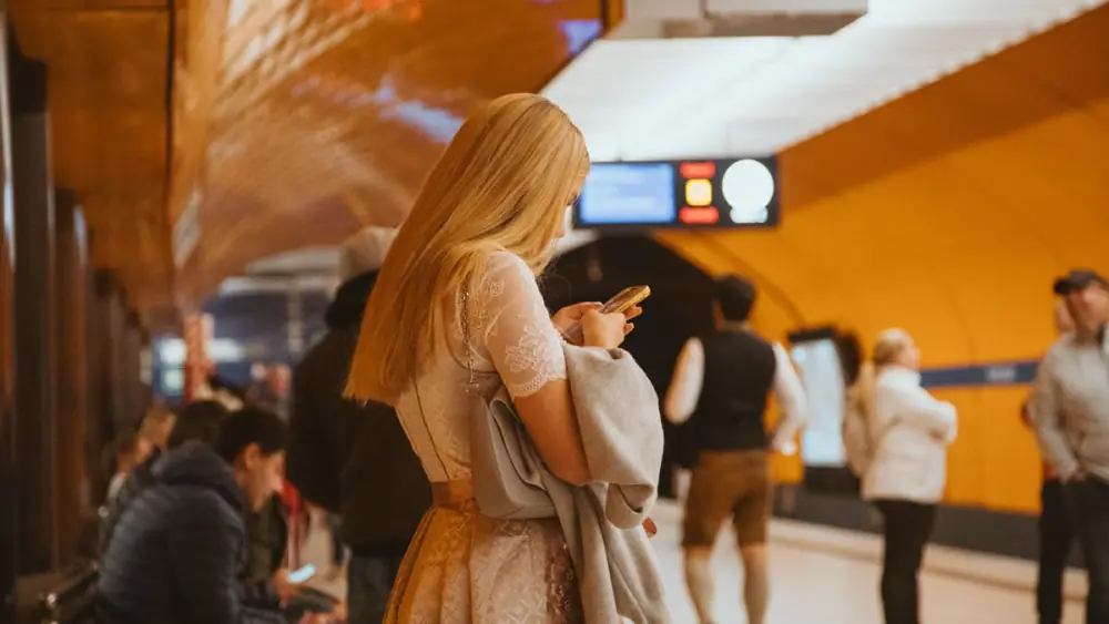 A woman on her phone on a warm-lit underground platform