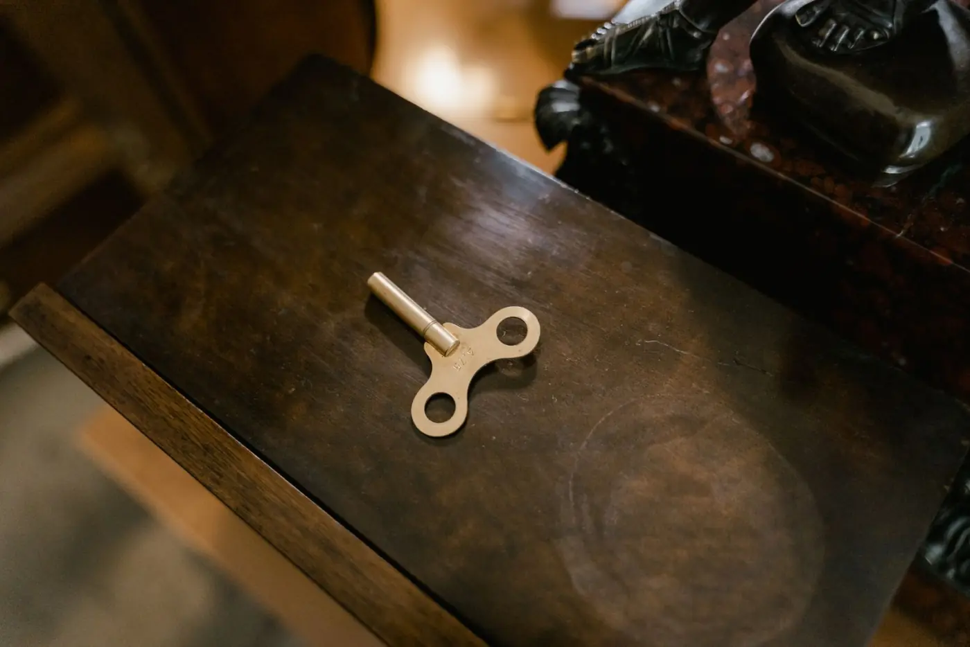 A single old key lying on a dark polished wooden surface